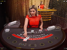 Live dealeren deler kort ud til to spillere på et sort blackjackbord. I baggrunden ses en anden live dealer